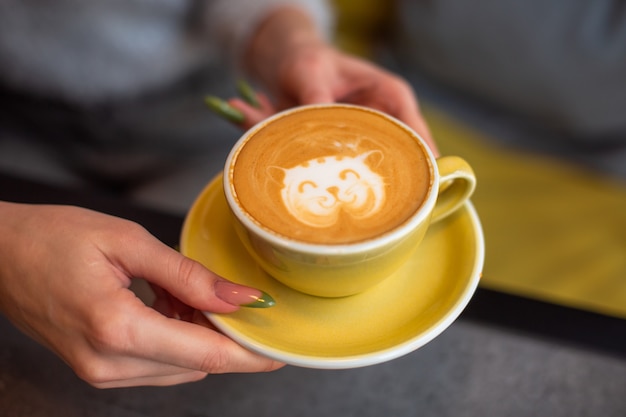 Foto kaffee-cappuccino in gelber tasse mit käsekuchen im café