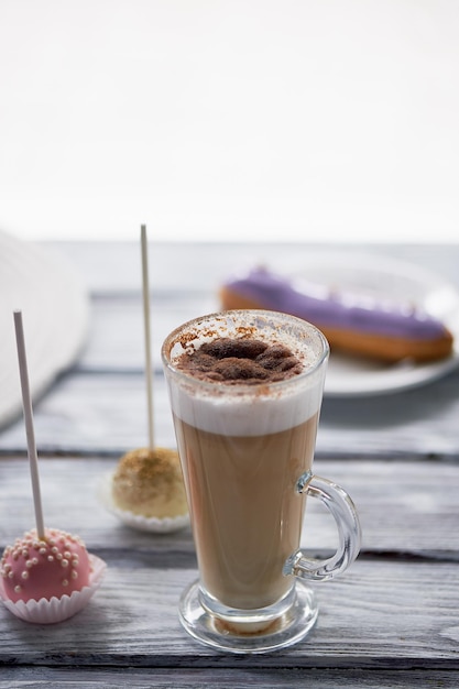 Kaffee-Cappuccino mit schönen Süßigkeiten auf Holzhintergrund Schöne Süßigkeiten