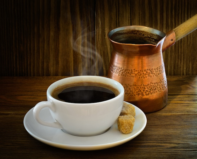 Kaffee-Cezve und Tasse mit frisch gebrühtem Kaffee auf Holzuntergrund