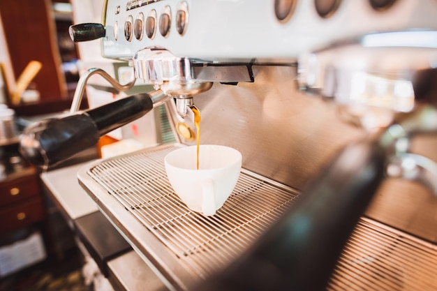 Kaffee, das aus dem Espresso-Gerät in eine Tasse im Laden gegossen wird