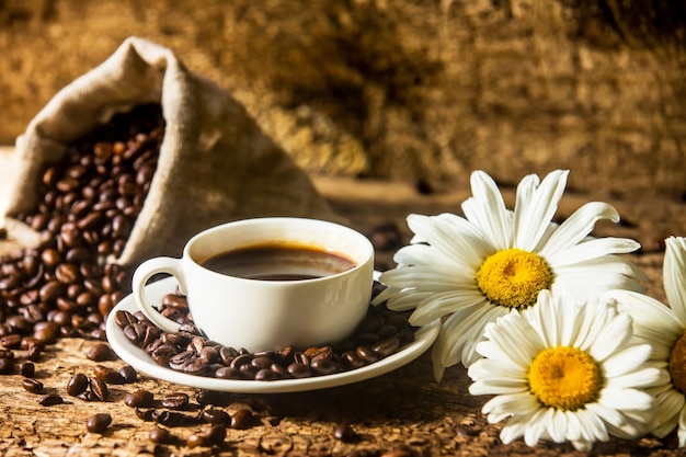 Kaffee Eine heiße Tasse Kaffee und geröstete Kaffeebohnen auf einem Holztisch Dunkler Hintergrund