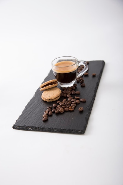 Kaffee-Espresso-Bohnen-Plätzchen-Steinschwarzes Brett-Glastasse
