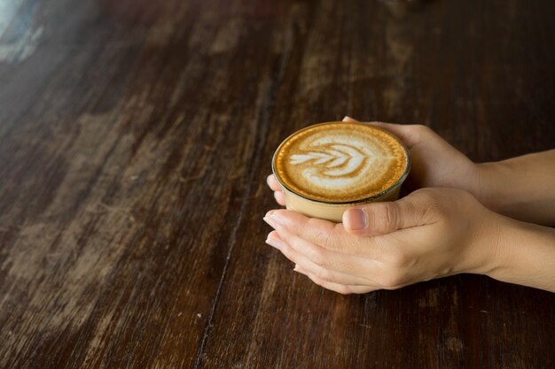 Kaffee in der Hand auf Tabelle mit Weichzeichnungsbild