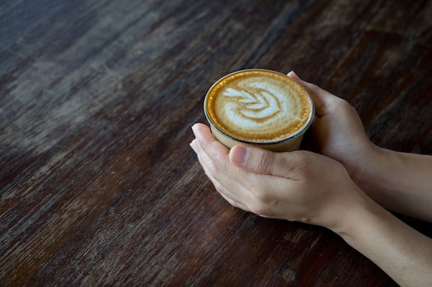 Kaffee in der Hand auf Tabelle mit Weichzeichnungsbild