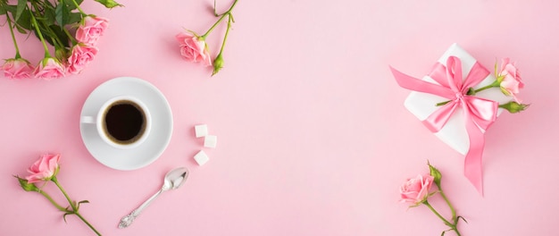 Kaffee in der weißen Cupgift-Box und rosa Rosen auf dem rosa Hintergrund Draufsicht Kopierbereich