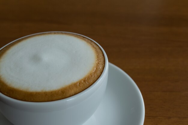 Kaffee in der weißen Schale auf hölzerner Tabelle