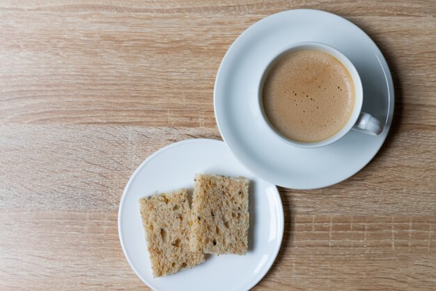 Kaffee in der weißen Tasse mit Vollkornbrot auf Holztisch, Frühstück mit gesundem Konzept