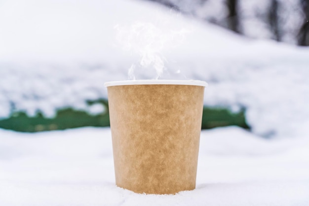 Kaffee in einem Pappbecher auf verschneitem Winterhintergrund Heißes Getränk bei kaltem Wetter Foto in hoher Qualität