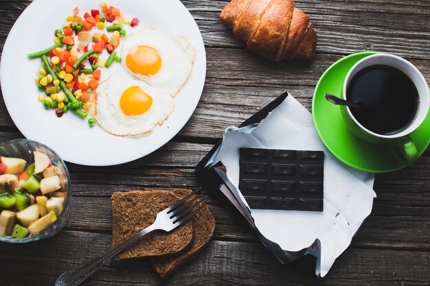 Kaffee in einer grünen Tasse auf Holzoberfläche mit Essen, leckeres Frühstück