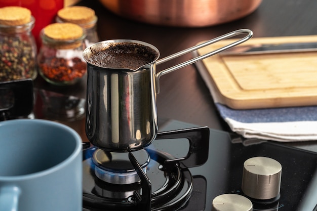 Kaffee in einer Stahltürke auf einem Gasherd kochen