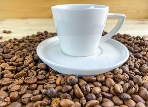 Kaffee in einer Tasse mit Untertasse und Kaffeebohnen auf dem Tisch