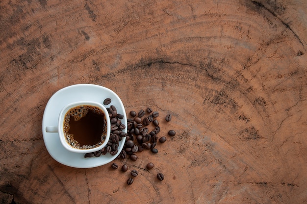 Foto kaffee in einer weißen schale und in den kaffeebohnen auf holztisch