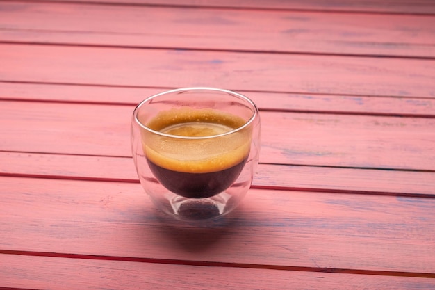 Kaffee in Glastasse auf rosa Holzhintergrund