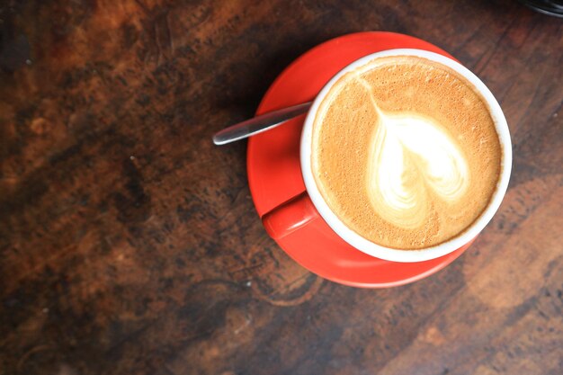 Kaffee in roter Tasse auf altem, dunklem, strukturiertem Holzhintergrund