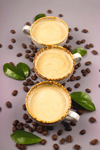 Kaffee in rustikalen Tassen zwischen Getreide und grünen Kaffeeblättern.