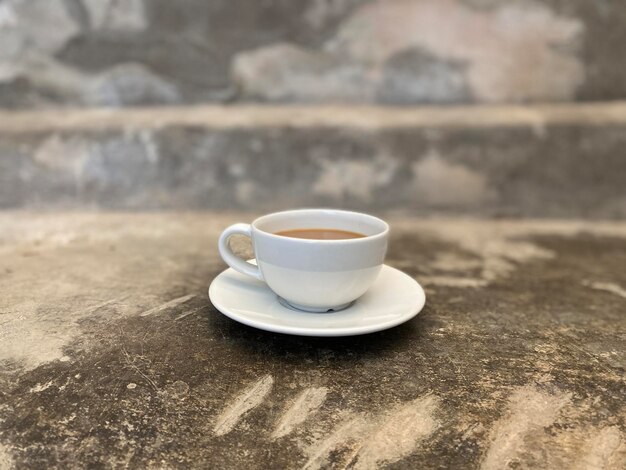 Kaffee in weißer Tasse auf Zementboden im Café