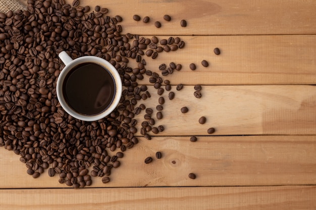 Kaffee in weißer tasse mit bohnen auf holztisch