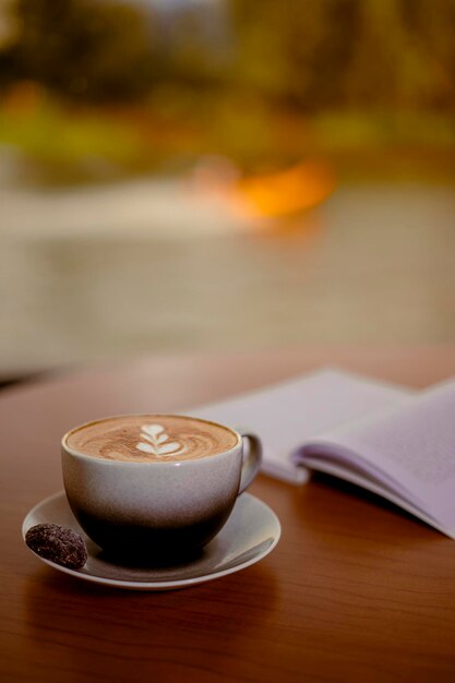 Foto kaffee latte und offenes buch auf holztisch mit seeblick