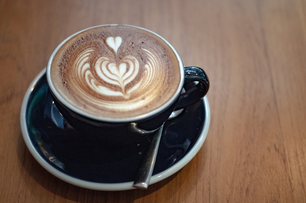 Foto kaffee lattekunst auf dem hölzernen schreibtisch im kaffeestubecafé