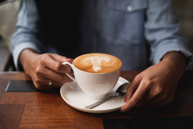 Kaffee Lattekunst im Café mit der Frauenhand