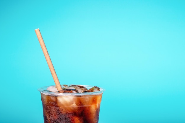 Kaffee mit Eis in einem Plastikglas mit einem Rohr auf blauem Hintergrund eine Kopie des Raums