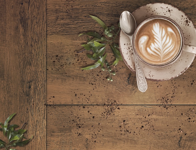 Foto kaffee mit lattekunst auf einem holztisch mit zerfallenen kaffeebohnen und