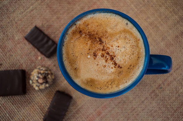 Kaffee mit Milch und Zimt in einer blauen Tasse mit etwas Schokolade