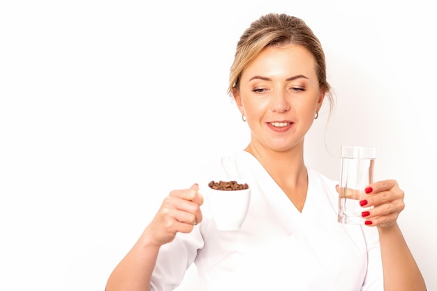 Kaffee mit Wasser Die Ernährungsberaterin hält eine Tasse Kaffeebohnen und ein Glas Wasser in den Händen auf weißem Hintergrund