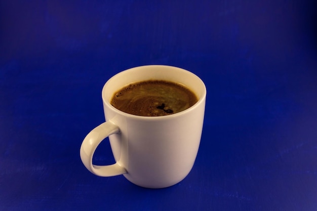Kaffee mit weichem Schaum in einer weißen Tasse auf blauem Hintergrund