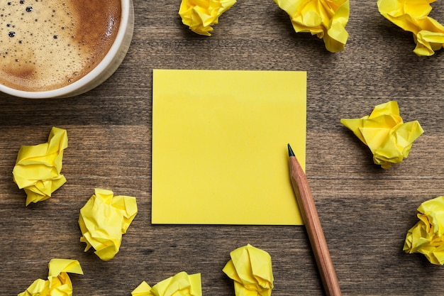 Kaffee und Bleistift mit zerknittertem Papier im Hintergrund