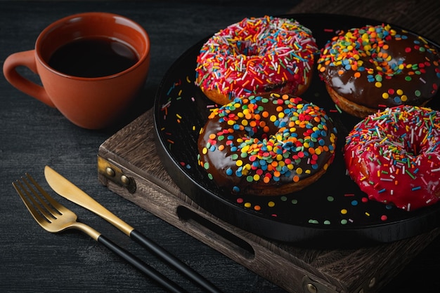 Kaffee und Donuts auf einem schwarzen Holztisch