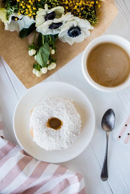 Kaffee und ein Donut mit frischen Blumen