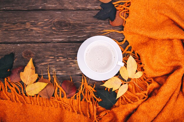 Kaffee und Herbstlaub auf Holzuntergrund