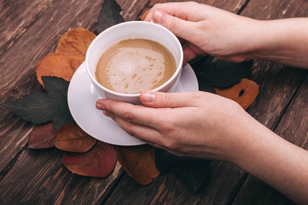 Kaffee und Herbstlaub auf Holzuntergrund