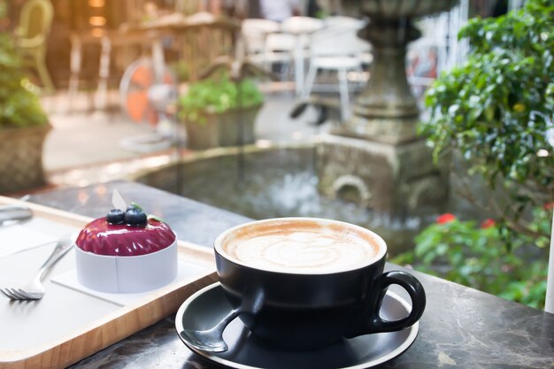 Kaffee und Kuchen auf Tabelle im Café mit schönem Gartenhinterhof