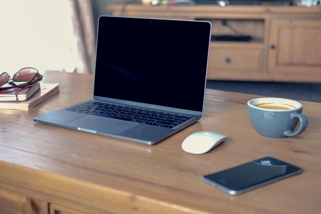 Kaffee und Laptop mit Mobiltelefon auf dem Tisch