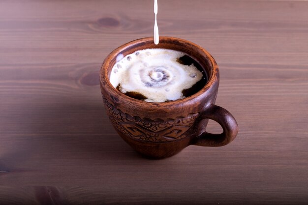 Kaffee und Milch in einem Tonkrug Milch wird in den Kaffee gegossen