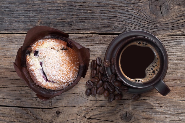 Kaffee und Muffin im braunen Wachspapier auf alter hölzerner Tischplatteansicht