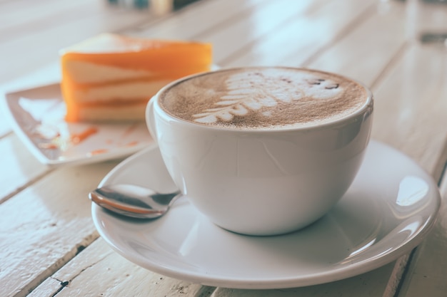 Kaffee und orange Kuchen auf Holztisch, Weichzeichnung, Weinleseton