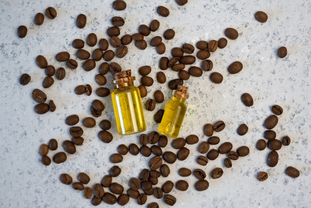 Foto kaffeeätherisches öl in einer glasflasche, kaffeebohnen auf grauem hintergrund