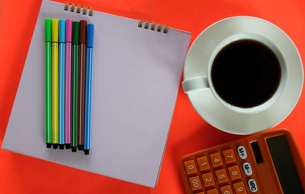 Foto kaffeebecher mit bunten stiften auf dem orangefarbenen bürotisch