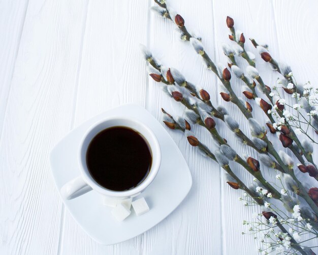 Foto kaffeebecher und frühlingsblumen auf weißem holzhintergrund nahaufnahme