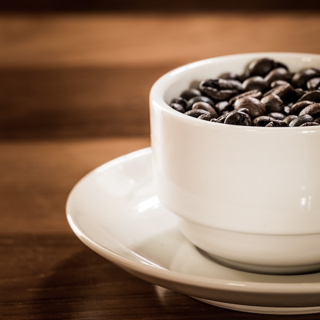 Kaffeebohne in der Tasse auf Holztisch