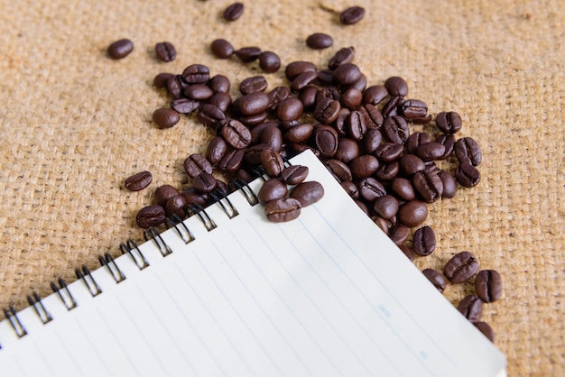 Foto kaffeebohne mit notizbuch auf leinwandhintergrund