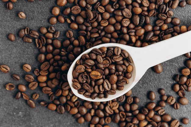 Kaffeebohnen auf Holzlöffel isoliert auf dunklem Hintergrund