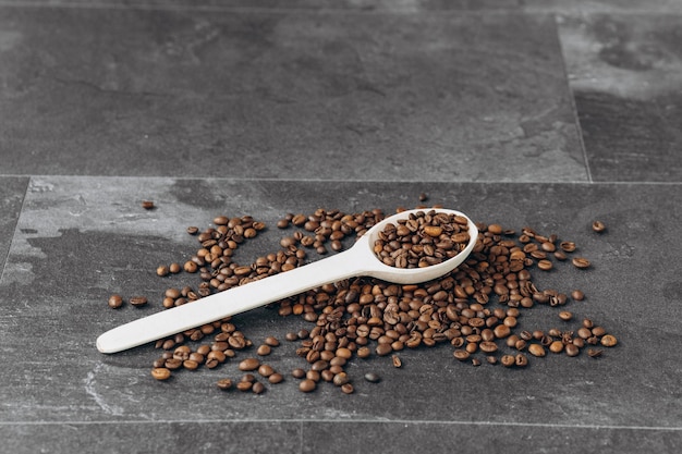 Kaffeebohnen auf Holzlöffel isoliert auf dunklem Hintergrund