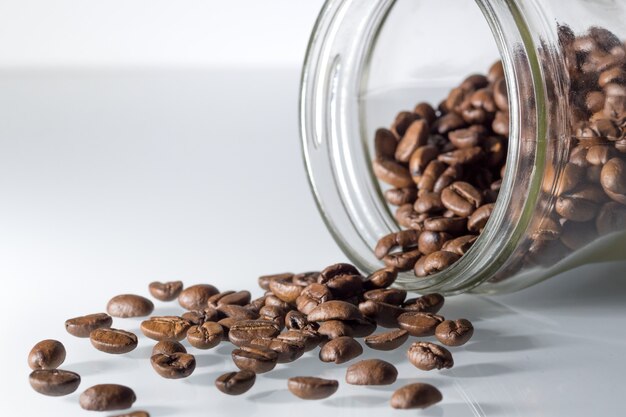 Kaffeebohnen auf weißem Tisch mit transparentem Glas