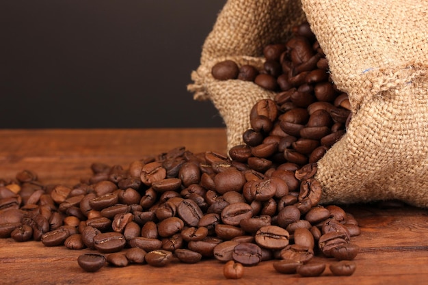 Kaffeebohnen in der Tasche auf dem Tisch auf dunklem Hintergrund