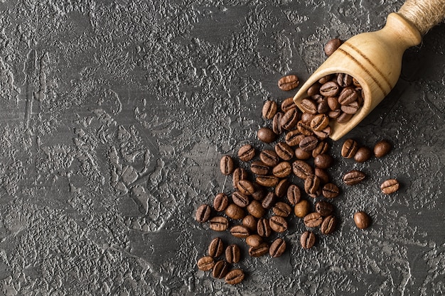 Kaffeebohnen in einem hölzernen Löffel auf Steinhintergrund