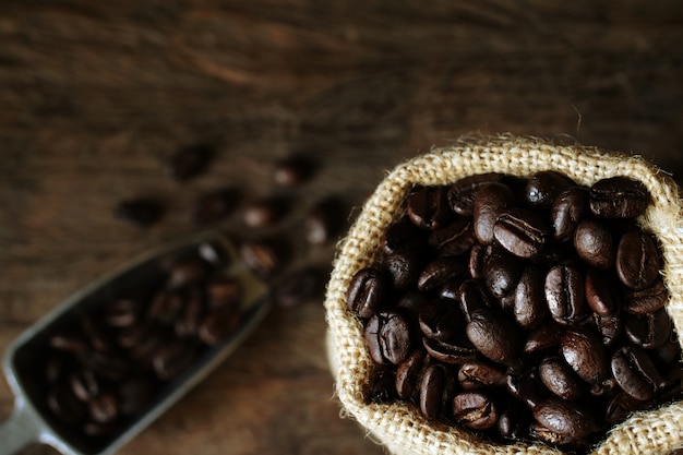 Kaffeebohnen in einem Sack auf Holztisch.